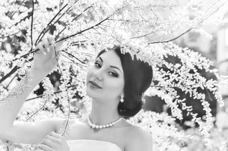 Beautiful bride with stylish make-up in white dress in spring gardenの写真素材