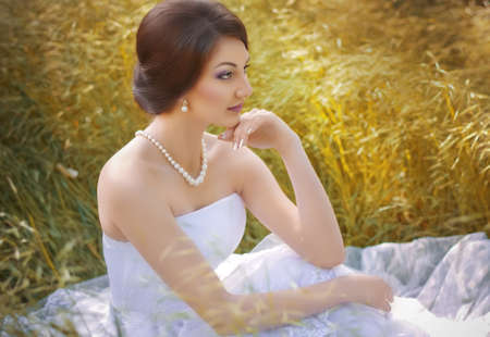 Beautiful bride with stylish make-up in white dress in spring gardenの写真素材
