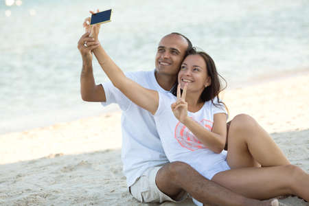 Happy couple portrait. Beautiful young caucasian adults in love walking on sunset beach.の写真素材