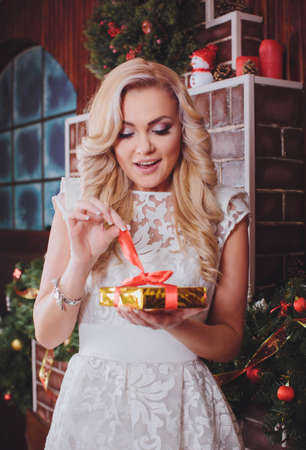 Beautiful young woman near a Christmas tree with giftsの写真素材