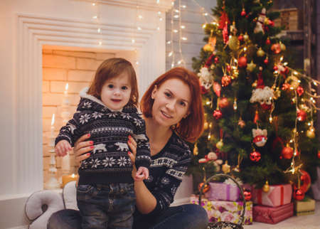 Beautiful mother with baby girl near a Christmas treeの写真素材