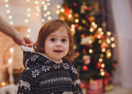 Beautiful baby girl near a Christmas tree with giftsの写真素材