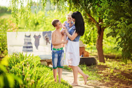 Home laundry. Smiling mother with little children using washingの写真素材