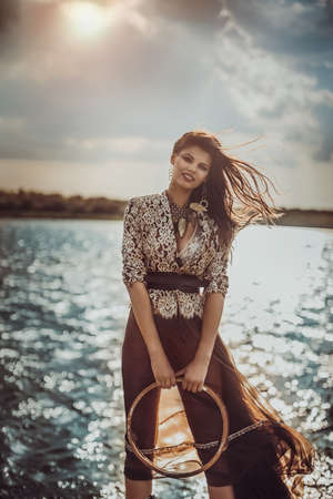 beautiful young girl with long dark hairs on the riversideの写真素材