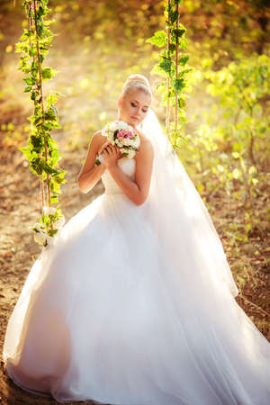 Beautiful bride in white dress in the autumn gardenの写真素材