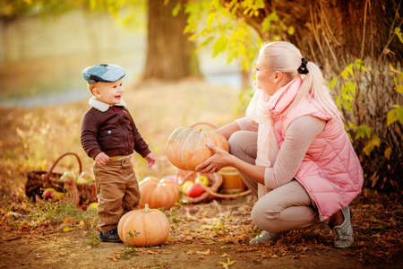 Beautiful baby boy and mother in autumn garden