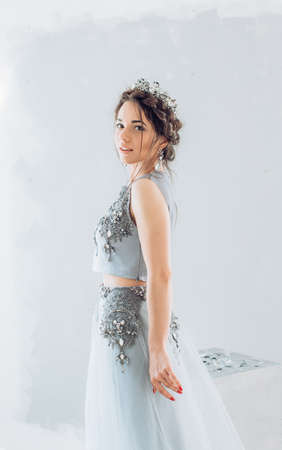 Portrait of a beautiful young woman with makeup in gray long fashion clothesの写真素材