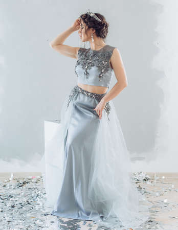 Portrait of a beautiful young woman with makeup in gray long fashion clothesの写真素材