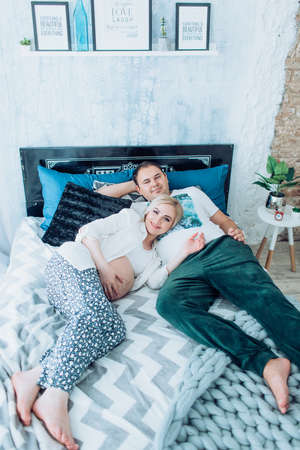 Beautiful pregnant woman with her husband in her bedroom