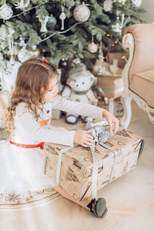 Beautiful little girl in white dress with Christmas tree decorationの写真素材