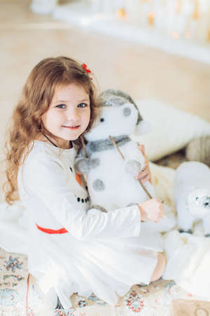 Beautiful little girl in white dress with Christmas tree decorationの写真素材