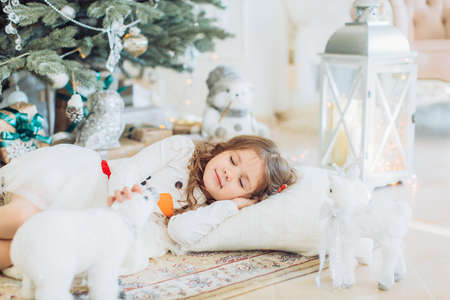Beautiful little girl in white dress with Christmas tree decorationの写真素材