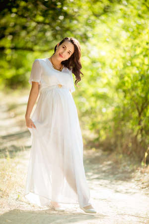 Beautiful pregnant woman in a green gardenの写真素材