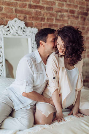 Beautiful pregnant woman with her husband in her bedroomの写真素材