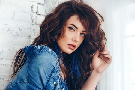 Portrait of beautiful young brunette woman with makeup in fashion blue clothes
