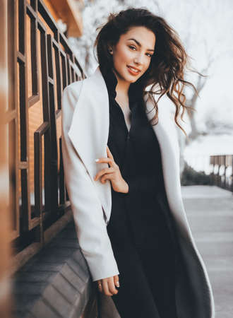 Portrait of beautiful young brunette woman with makeup in white fashion clothes