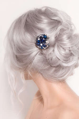 Portrait of a beautiful young blonde woman with makeup and a beautiful hair-do by the decorated stylish bijouterieの写真素材