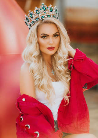 Portrait of beautiful blonde woman with makeup in fashion bright clothes and crownの写真素材