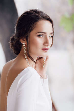 Beautiful brunette girl with stylish make-up in white dressの写真素材