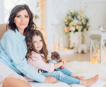 Happy girl with mother near Christmas tree