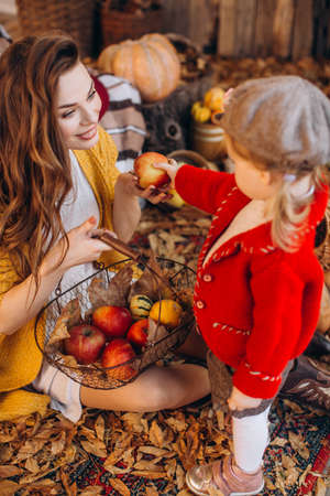 Beautiful baby girl in autumn garden with motherの写真素材