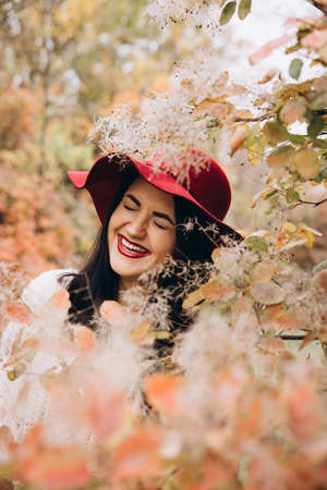 Beautiful girl in red hat in autumn gardenの写真素材