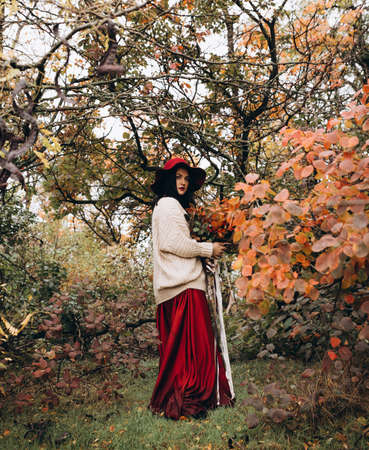 Beautiful girl in red hat in autumn gardenの写真素材