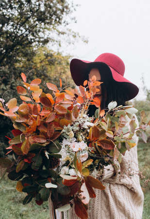 Beautiful girl in red hat in autumn gardenの写真素材