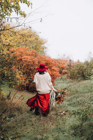 Beautiful girl in red hat in autumn gardenの写真素材
