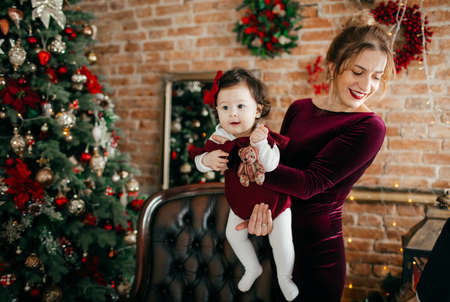Baby girl and mother near christmas tree