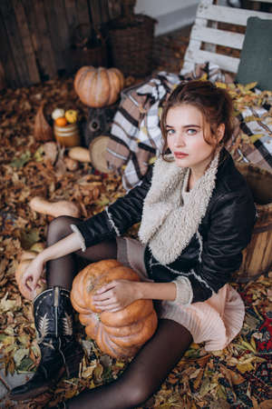 Beautiful girl in autumn garden with yellow flowers and pumpkinsの写真素材