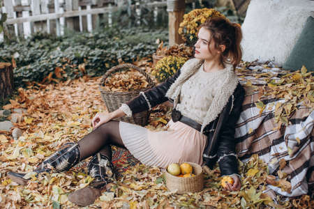 Beautiful girl in autumn garden with yellow flowers and pumpkinsの写真素材
