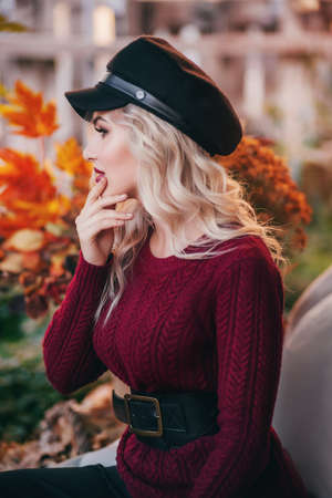 Beautiful blonde woman in autumn garden with yellow flowersの写真素材