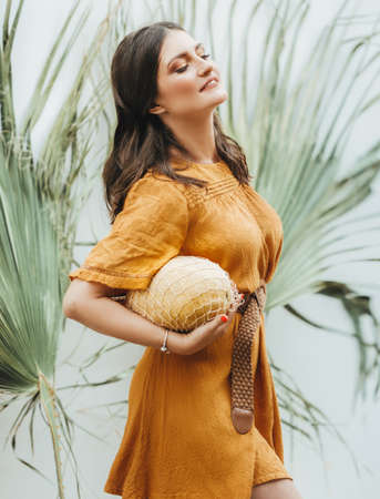 Beautiful young woman in orange dress with melon