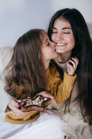 Stock Photo - Beautiful girl with a little girl eat nuts