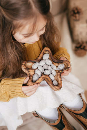 Stock Photo - Beautiful little girl with nuts on with wooden christmas decorの写真素材