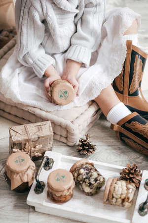 Beautiful little girl with jars in which honey and nuts with wooden christmas decorの写真素材