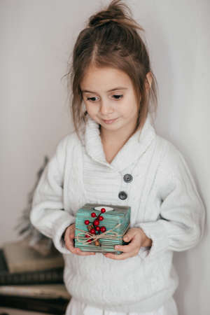 Portrait of a little beautiful girl with a wooden candlestick in a Christmas decor