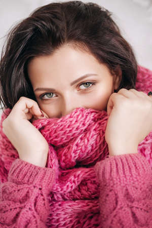 Portrait of beautiful young brunette woman with makeup in pink sweater