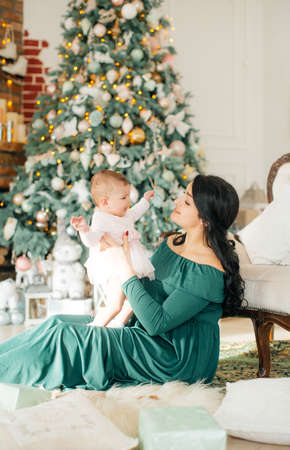 Baby girl and mother near christmas treeの写真素材