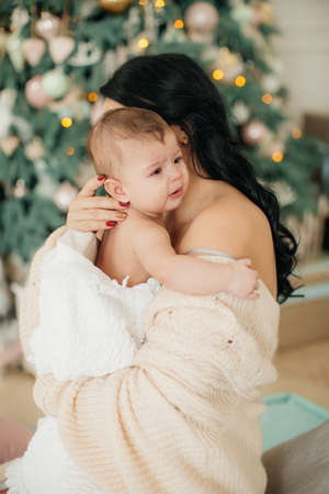 Baby girl and mother near christmas treeの写真素材