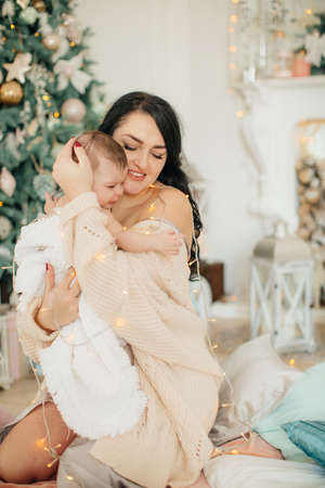 Baby girl and mother near christmas tree