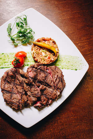 Stock Photo - Ribeye steak with vegetable dressing on a white plateの写真素材