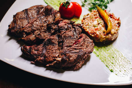 Stock Photo - Ribeye steak with vegetable dressing on a white plateの写真素材
