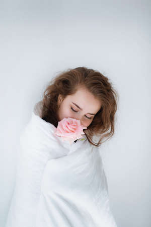 Stock photo - Sweet girl with pink rose under the covers in her bedの写真素材