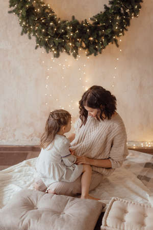 Photo of a little beautiful girl and her mother with a Christmas wreathの写真素材
