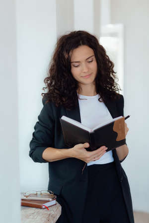 Stock Photo - Young female professional smiling to camera is with a notebook, taking notes. Professional psychologistの写真素材