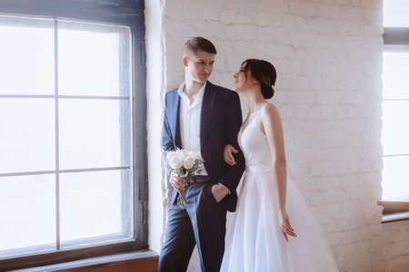 Happy bride in white dress and groom on their wedding, Bridal couple, Happy Newlywed woman and man. Loving wedding couple. in a light interiorの写真素材