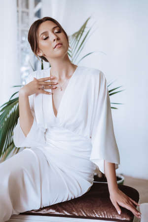 Beautiful sophisticated bride in a wedding dress in a bright roomの写真素材