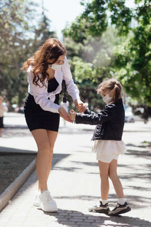 A woman and a little daughter  in medical masks walk on the street during the coronavirus and...